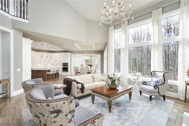 living room featuring a high ceiling, baseboards, a chandelier, and wood finished floors