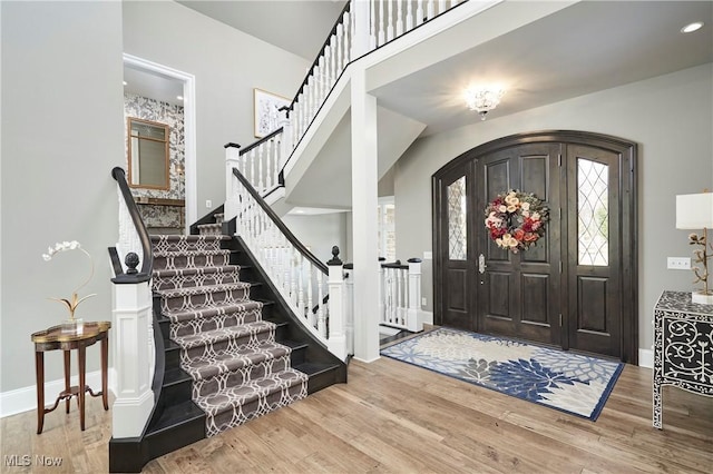 foyer entrance featuring arched walkways, wood finished floors, stairs, and baseboards