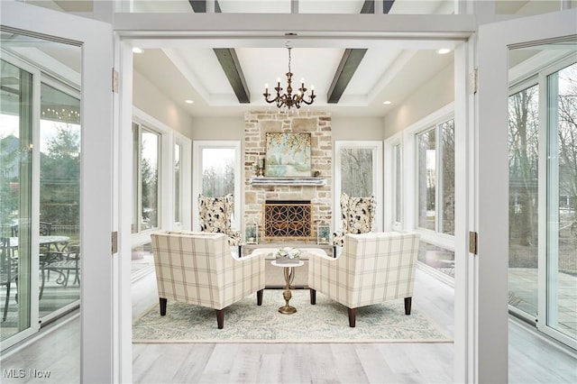 sunroom / solarium with a notable chandelier, a fireplace, and beamed ceiling