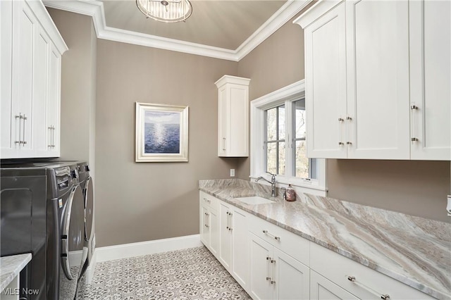 laundry area featuring separate washer and dryer, a sink, baseboards, cabinet space, and crown molding