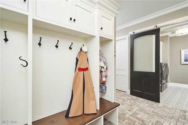 mudroom with brick floor, washer and clothes dryer, a barn door, ornamental molding, and baseboards