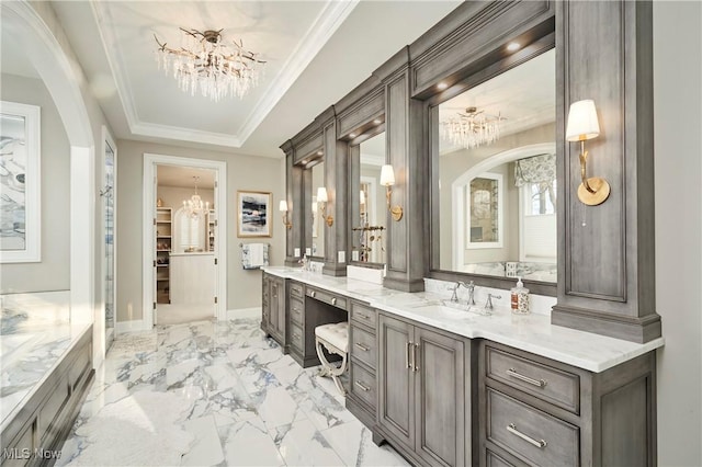 bathroom with ornamental molding, a sink, marble finish floor, a tray ceiling, and a notable chandelier