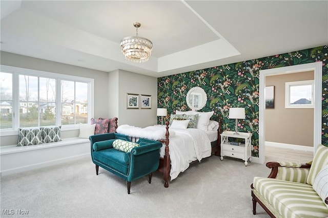 carpeted bedroom featuring baseboards, a chandelier, a raised ceiling, and wallpapered walls