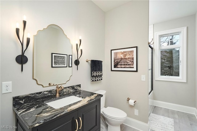 bathroom with toilet, baseboards, bath / shower combo with glass door, and vanity