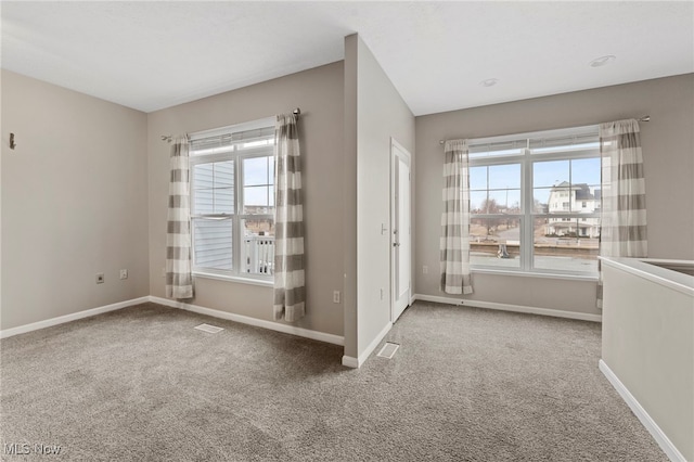 carpeted spare room featuring visible vents and baseboards