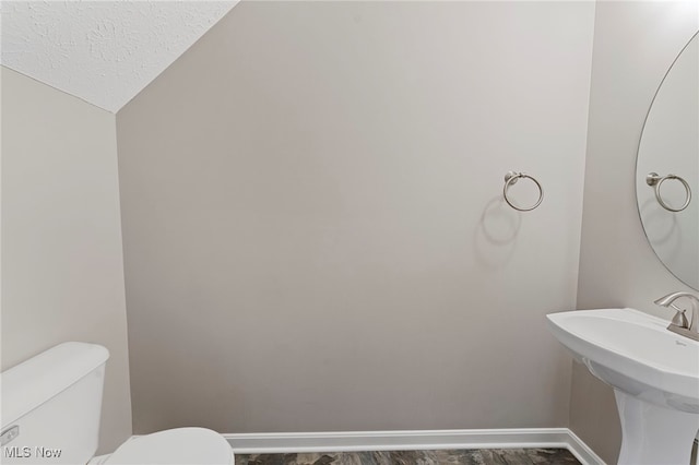 bathroom with a textured ceiling, a sink, toilet, and baseboards