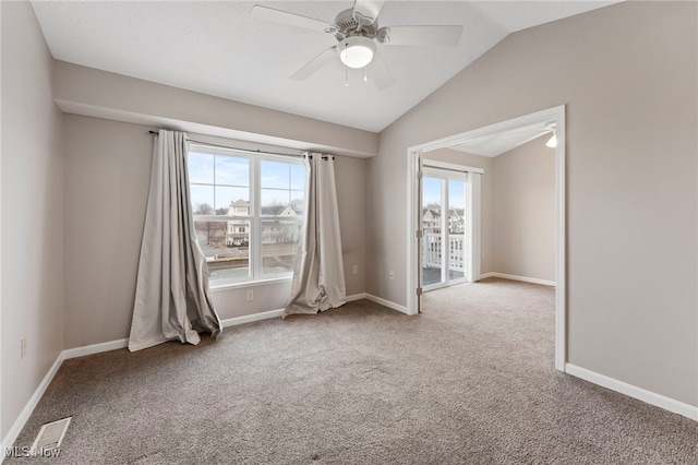 empty room with lofted ceiling, carpet, visible vents, and a wealth of natural light