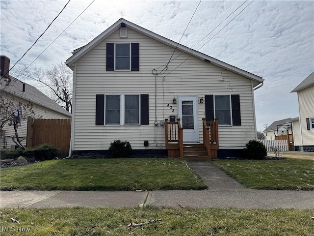 bungalow featuring a front lawn and fence