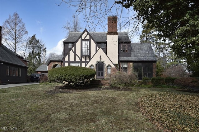 back of house with entry steps, a yard, a chimney, and stucco siding