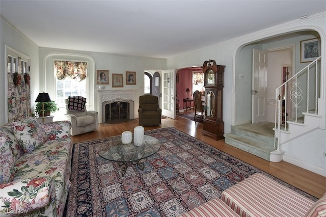 living area with arched walkways, a healthy amount of sunlight, stairway, and wood finished floors