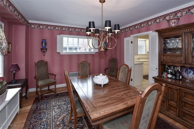 dining room featuring light wood-style floors, baseboards, a chandelier, and ornamental molding