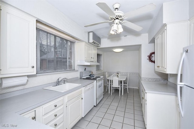 kitchen featuring white appliances, white cabinets, under cabinet range hood, a sink, and a wall mounted AC