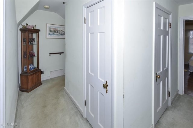 corridor featuring light carpet, lofted ceiling, and baseboards