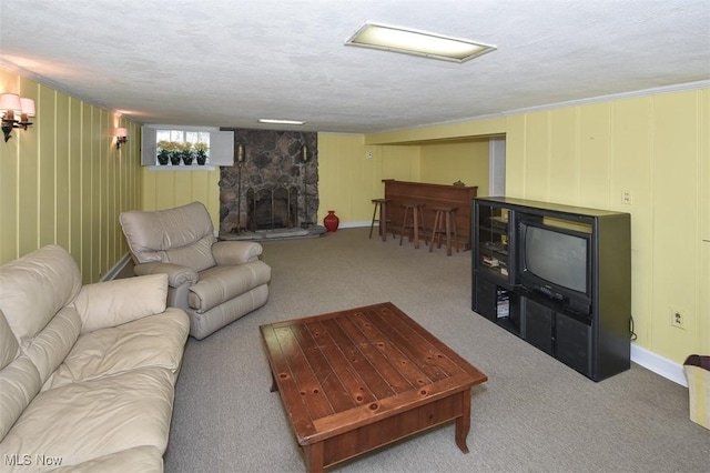 living area with carpet, baseboards, a stone fireplace, and a textured ceiling