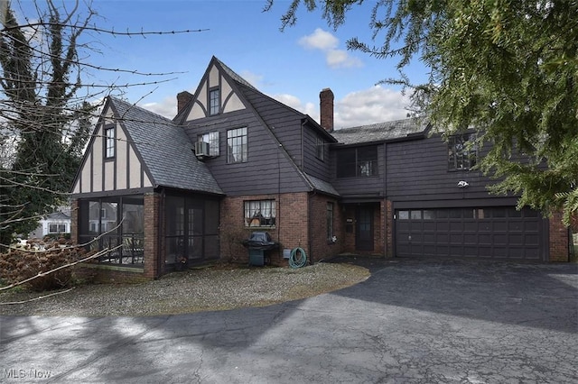 english style home featuring brick siding, driveway, and a chimney