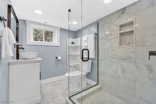 full bath featuring toilet, a stall shower, vanity, and baseboards