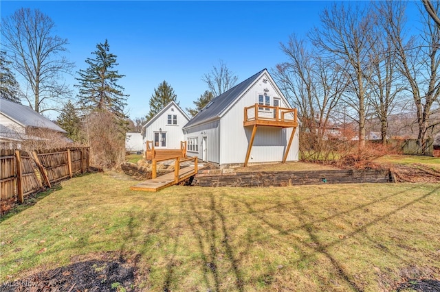 rear view of house with fence, a deck, and a lawn