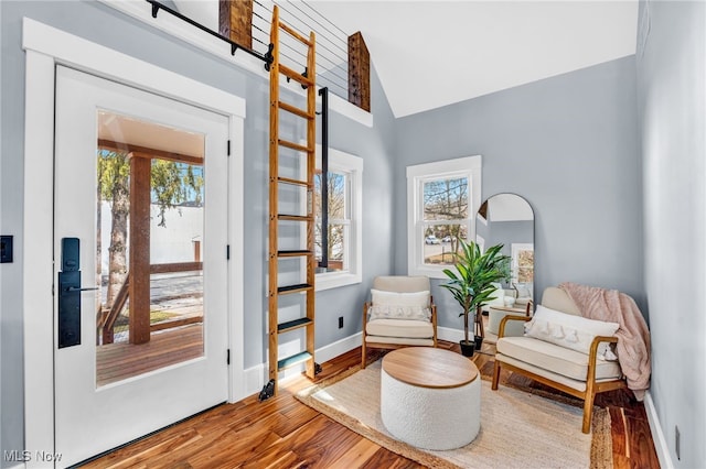 living area featuring lofted ceiling, baseboards, and wood finished floors