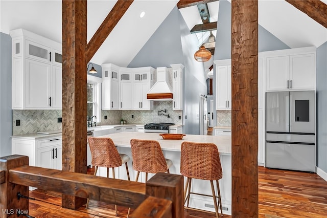 kitchen with custom range hood, stove, a kitchen breakfast bar, light countertops, and fridge