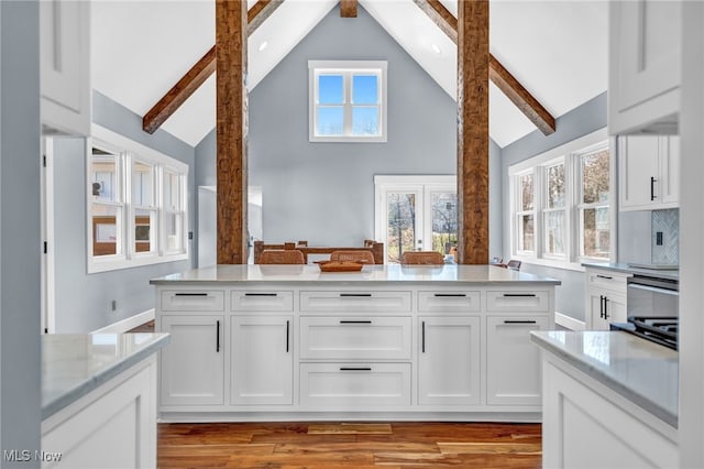 kitchen featuring white cabinets, beam ceiling, and a healthy amount of sunlight