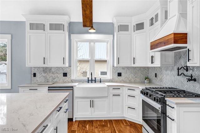 kitchen featuring a sink, white cabinets, stainless steel dishwasher, gas stove, and custom range hood