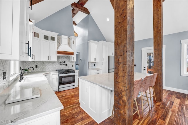 kitchen featuring light stone counters, dark wood-type flooring, a sink, gas range, and custom range hood