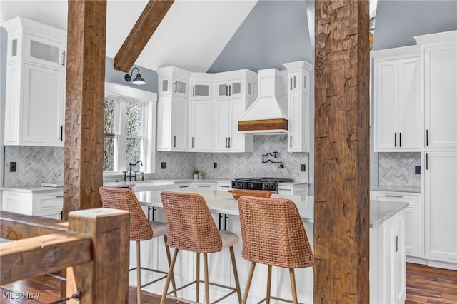 kitchen featuring beam ceiling, light countertops, custom exhaust hood, and white cabinetry