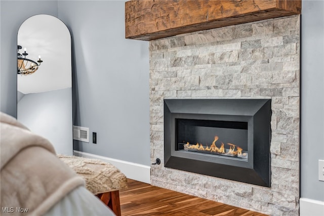 room details featuring baseboards, a lit fireplace, visible vents, and wood finished floors