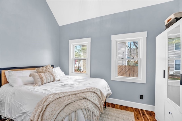 bedroom with vaulted ceiling, wood finished floors, and baseboards