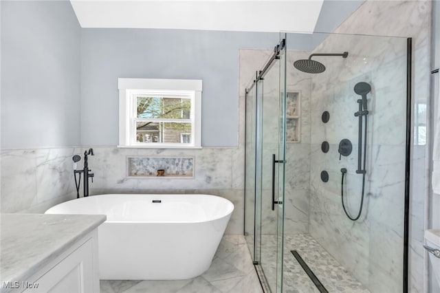 bathroom with marble finish floor, vanity, a soaking tub, and a stall shower