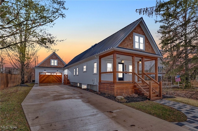 view of front facade with a garage, metal roof, covered porch, fence, and an outdoor structure