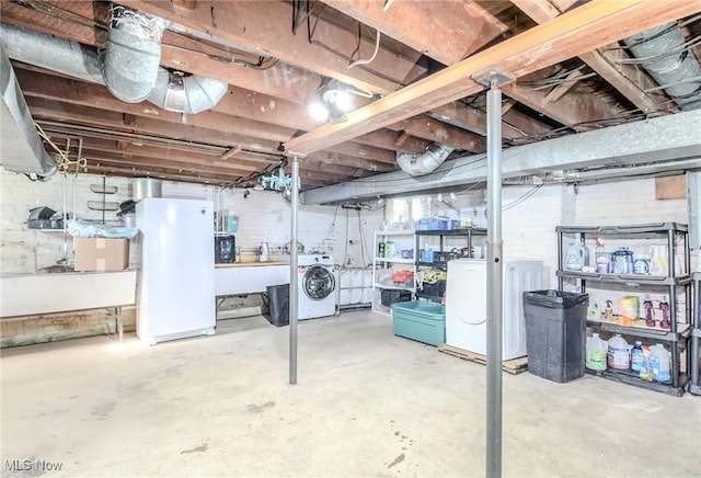 unfinished below grade area featuring freestanding refrigerator, refrigerator, and washer and clothes dryer