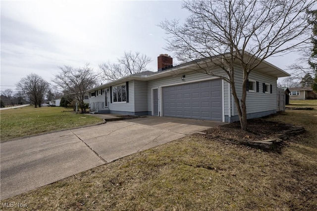 view of side of home featuring driveway, a chimney, an attached garage, and a lawn