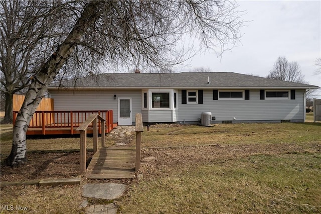 rear view of house with central air condition unit, roof with shingles, a lawn, and a wooden deck