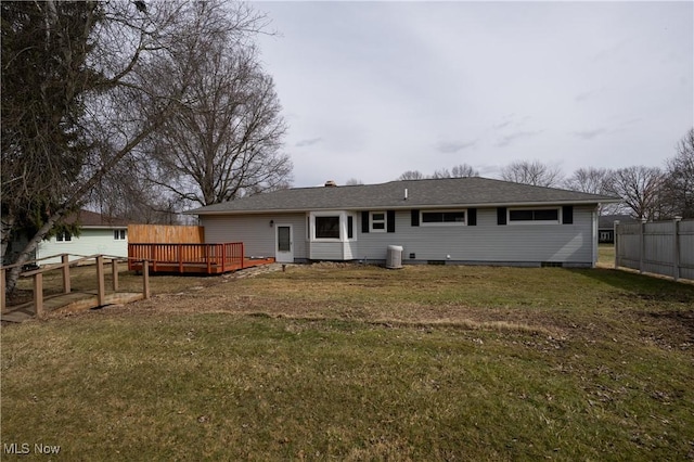 rear view of property with fence, a wooden deck, and a lawn