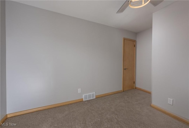 unfurnished room with carpet floors, baseboards, visible vents, and a ceiling fan