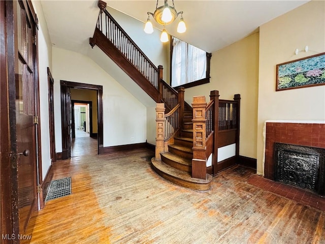 staircase featuring baseboards, visible vents, a tiled fireplace, and wood finished floors