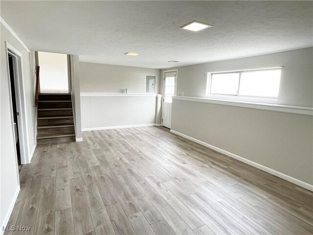 spare room featuring baseboards, stairway, a textured ceiling, and wood finished floors