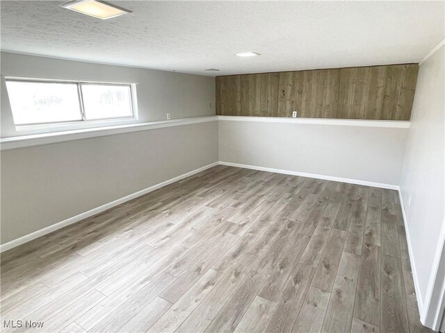 empty room featuring a textured ceiling, baseboards, and wood finished floors