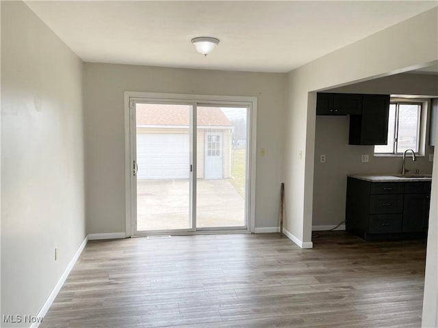 unfurnished dining area featuring light wood-type flooring, a wealth of natural light, and a sink