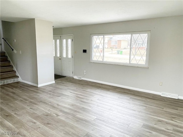 interior space featuring baseboards, stairs, visible vents, and wood finished floors