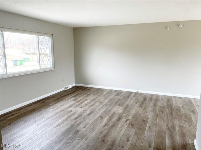 spare room featuring wood finished floors and baseboards