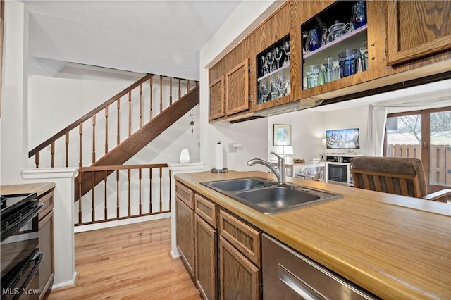 kitchen with range with two ovens, a sink, light countertops, brown cabinets, and light wood finished floors