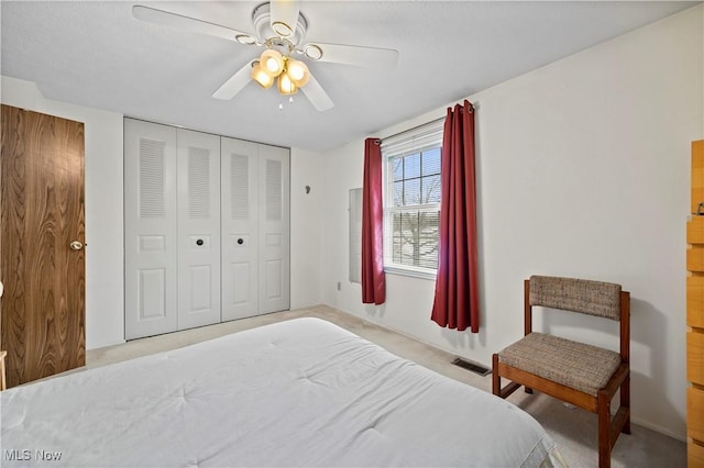 carpeted bedroom with a closet, visible vents, and a ceiling fan