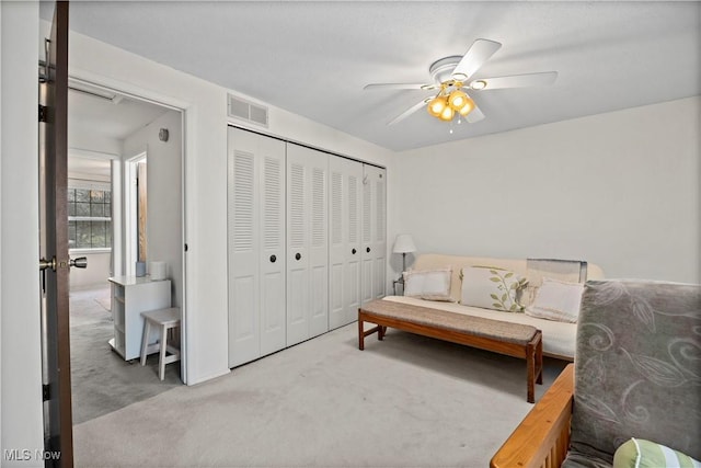 living area with a ceiling fan, carpet flooring, and visible vents