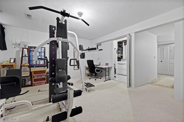 exercise room featuring a textured ceiling, washer / clothes dryer, and visible vents