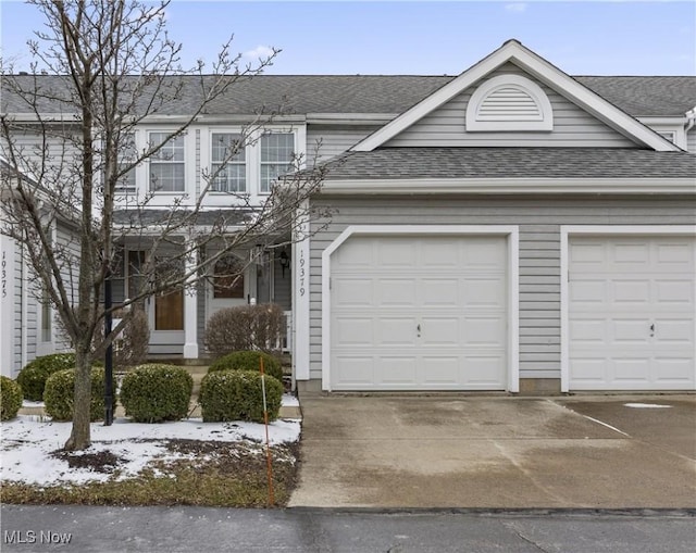 view of front of home with concrete driveway, roof with shingles, and an attached garage