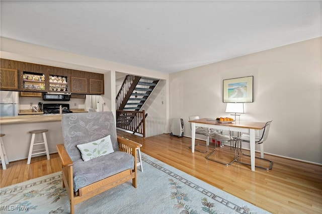 sitting room featuring stairs, baseboards, and light wood-style floors