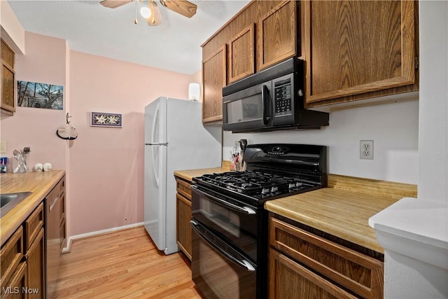 kitchen featuring a ceiling fan, light wood-style flooring, brown cabinets, light countertops, and black appliances