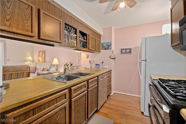 kitchen featuring ceiling fan, a sink, light countertops, dishwasher, and light wood finished floors